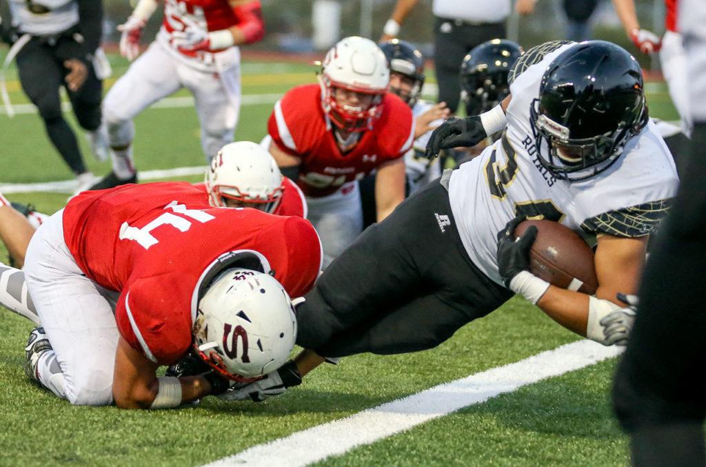 Lynnwood’s Michael Kirkman falls across the goal line with Snohomish’s Kevin Lopez attempting a tackle during a game Friday night at Veterans Memorial Stadium. (Kevin Clark / The Herald)
