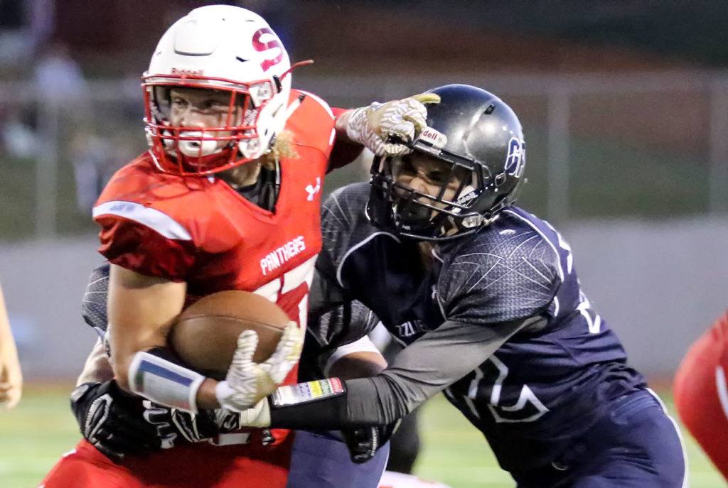 Snohomish’s Keegan Stich rushes for yardage with Glacier Peak’s Bo Burns attempting a tackle Friday night at Veterans Memorial Stadium in Snohomish. (Kevin Clark / The Herald)
