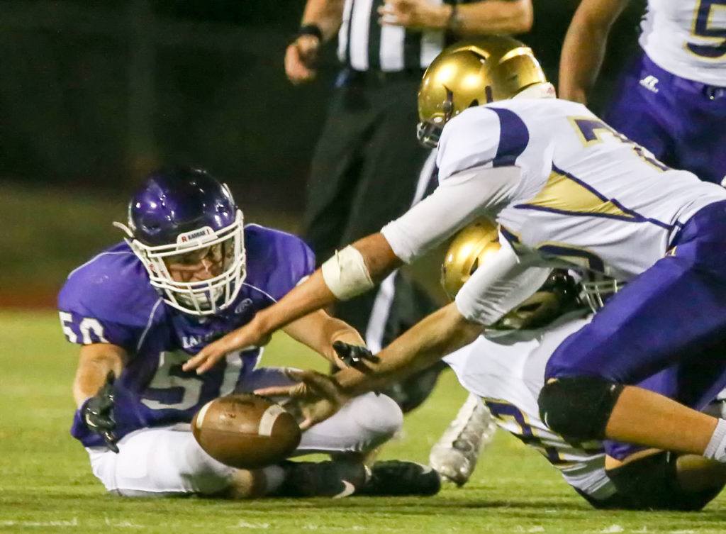 Kamiak’s Connor Jones beats Oak Harbor’s Ozell Jackson to the fumble by Oak Harbor’s Tamarik Hollins-Passmore during a game Thursday night at Goddard Stadium in Everett. (Kevin Clark / The Herald)
