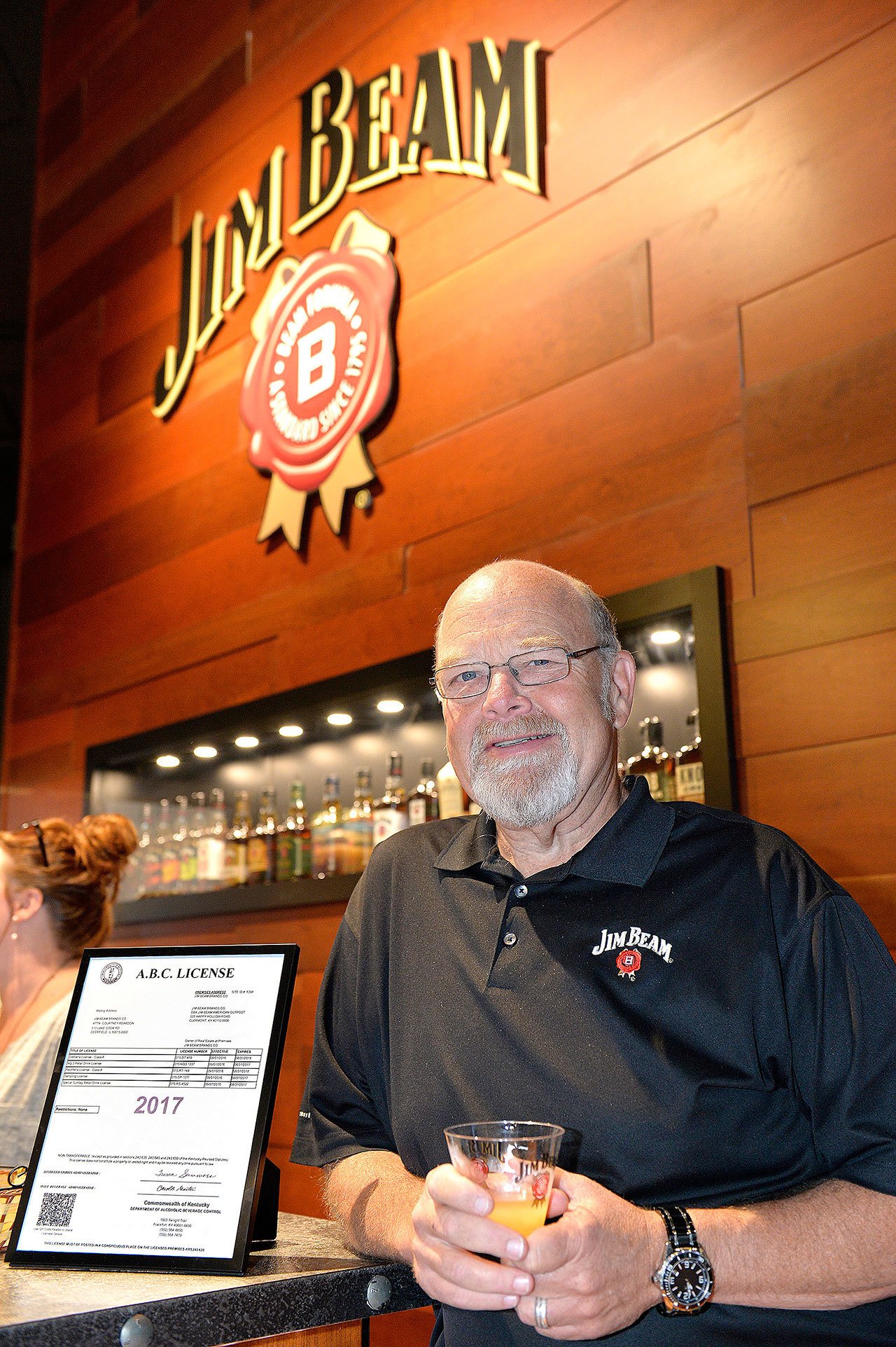 Fred Noe, Master Distiller of Jim Beam, stands next to the liquor license in the new Jim Beam Bourbon Bar on the distillery grounds Wednesday in Clermont, Kentucky. (AP Photo/Timothy Easley)