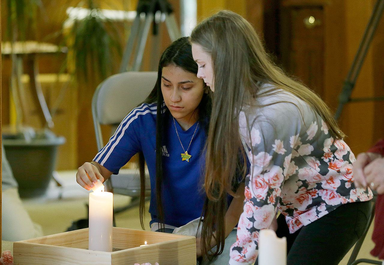 Rachel Marsh (right) and Selena Orozco, both 15, light candles at a prayer service on Saturday in Sedro-Woolley to mourn victims of Friday’s fatal shooting of five people at Cascade Mall in nearby Burlington. (AP Photo/Ted S. Warren)