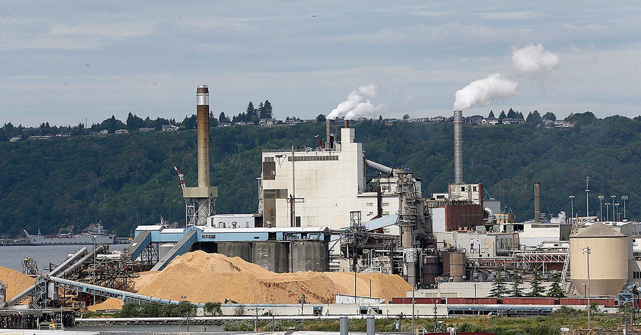 In this June 1 photo, piles of wood chips sit near the RockTenn paper mill in Tacoma. Washington state environmental regulators finalized a new rule Thursday to limit greenhouse gas emissions from large emitters, including the mill. (AP Photo/Ted S. Warren, file)