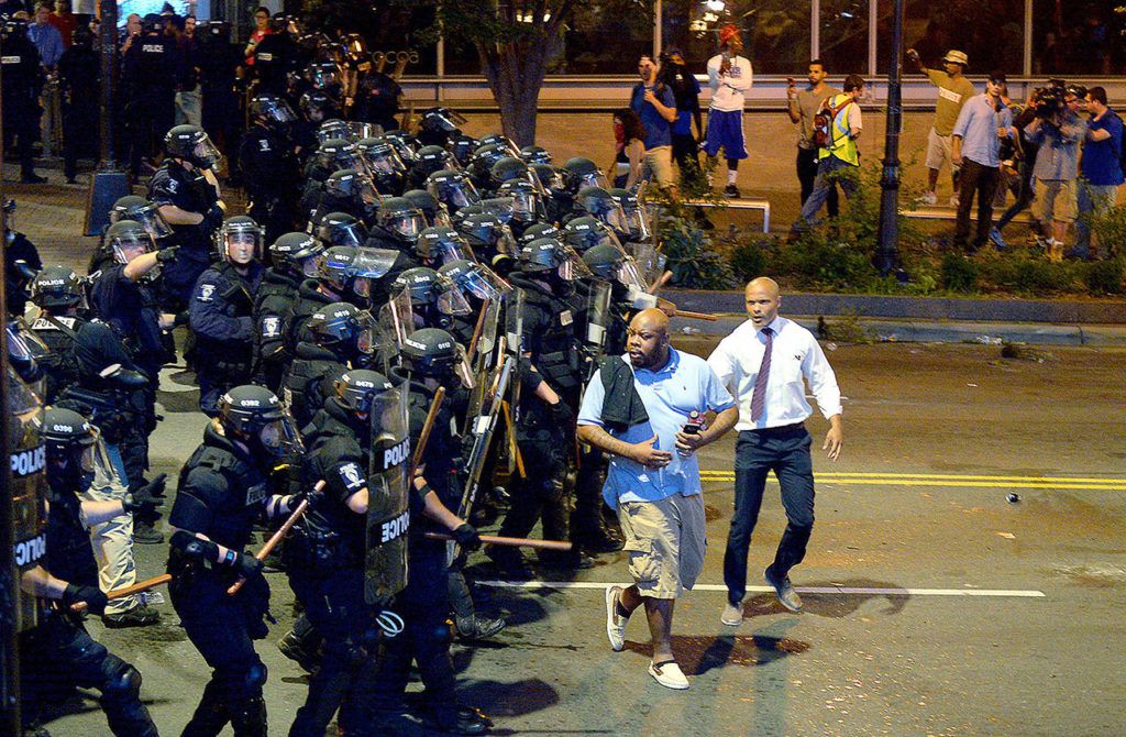 Charlotte-Mecklenburg police officers push protesters from an intersection near the Epicentre in Charlotte, North Carolina, on Wednesday. Authorities tried to quell public anger Wednesday after a police officer shot a black man, but a dusk prayer vigil turned into a second night of violence, with police firing tear gas at angry protesters and a man being critically wounded by gunfire. North Carolina’s governor declared a state of emergency in the city. (Jeff Siner/The Charlotte Observer via AP)
