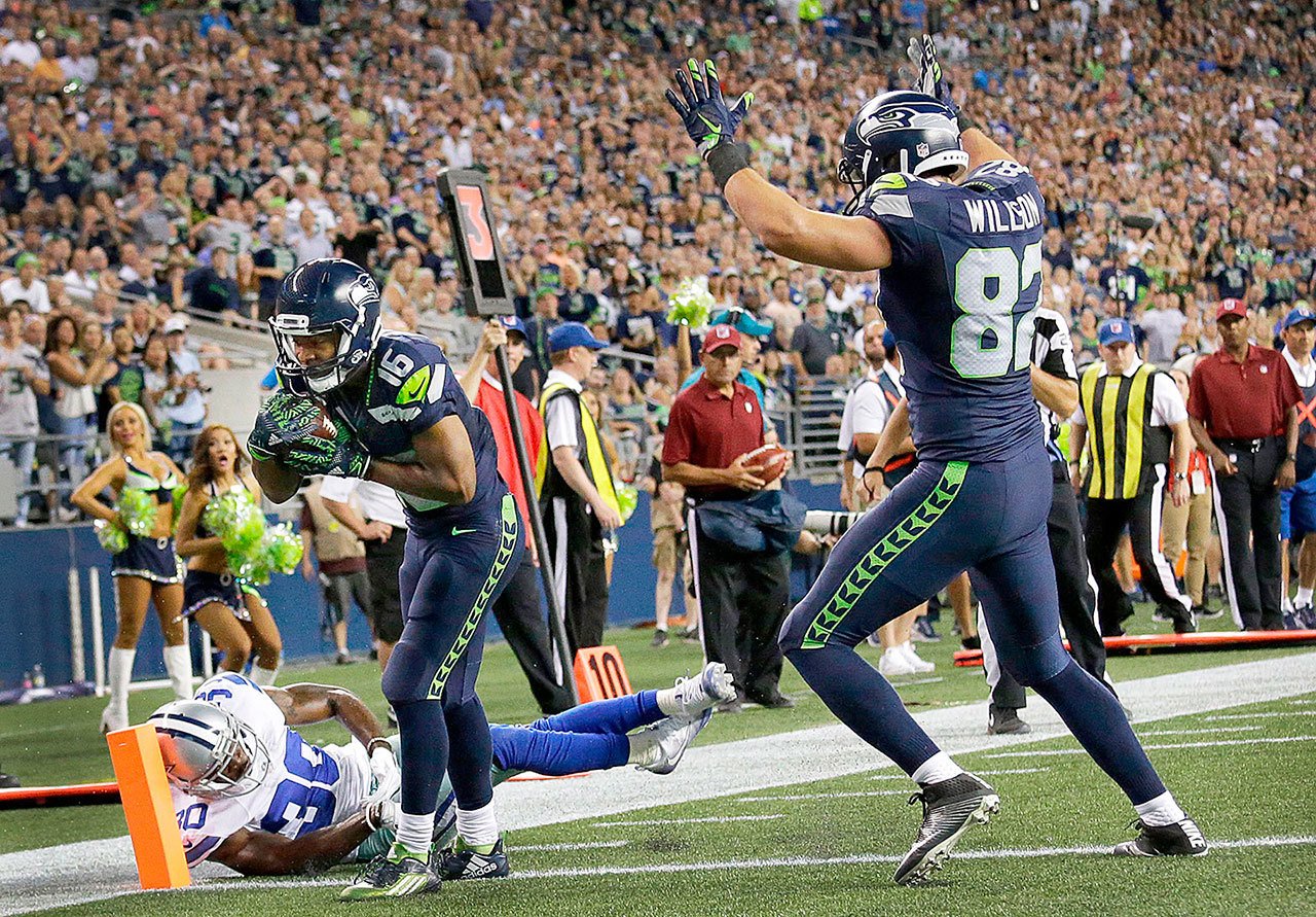 Seahawks wide receiver Tyler Lockett (16) scores a touchdown past Cowboys cornerback Anthony Brown (left) as Seahawks tight end Luke Willson signals the score during the second half of a preseason game Aug. 25 in Seattle. (AP Photo/Elaine Thompson)