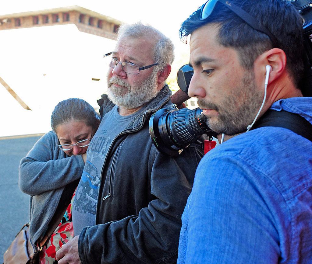 Arcan Cetin’s stepfather David Marshall is swarmed by the media outside the Skagit County District Court on Monday, moments after Cetin appeared in court under a magistrate’s warrant which will give Skagit County prosecutors 30 days to file official charges against him in the Cascade Mall shooting where five people were murdered on Friday in Burlington. (Brandy Shreve/Skagit Valley Herald via AP)
