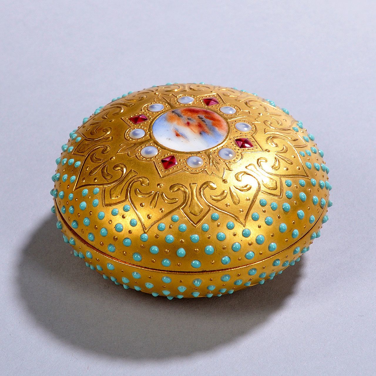 This round Coalport box with a lid may have been made to hold powder. It has turquoise “jewels” and a medallion. Price at auction, $461. (Cowles Syndicate Inc.)