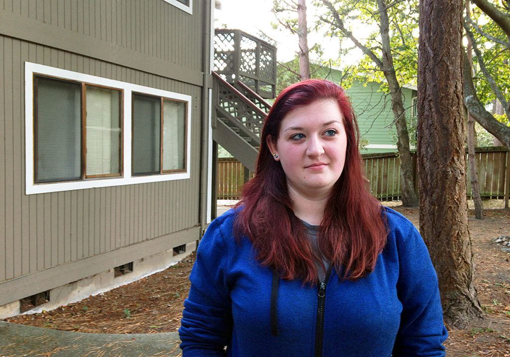 Amber Cathey, next-door neighbor and former high school classmate of Cascade Mall shooting suspect Arcan Cetin, stands in front of their building in this Oak Harbor complex Sunday. As a neighbor, she said he was “creepy, rude and obnoxious” and she was so frightened by him that she complained to apartment management and kept a Taser by her front door. (AP Photo/Martha Bellisle)
