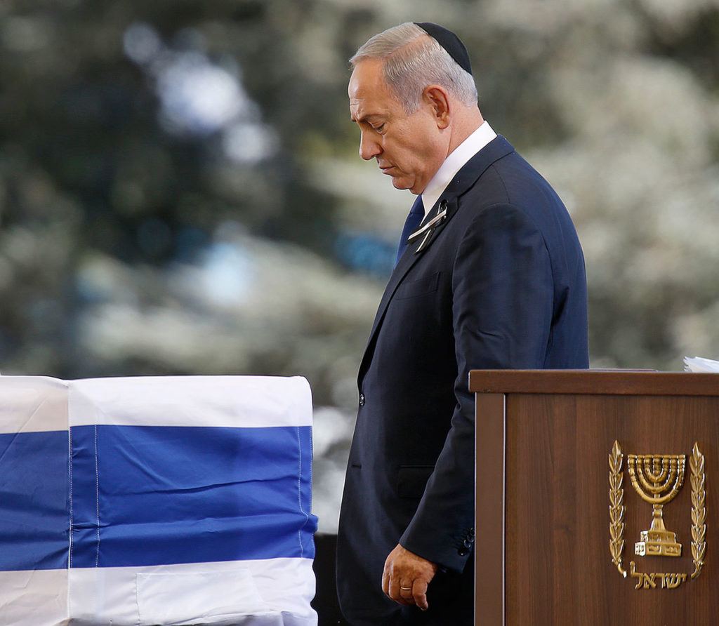 Israeli Prime Minister Benjamin passes the flag-draped coffin of former Israeli President Shimon Peres after speeching during his funeral at the Mount Herzel national cemetery in Jerusalem on Friday. (AP Photo/Ariel Schalit)
