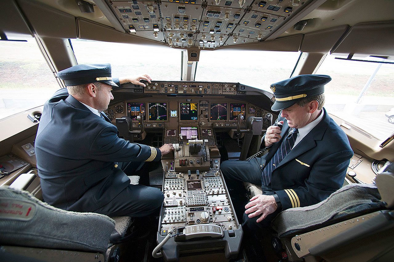 United Airlines Capt. Tommy Holloman, left, and Capt. Chuck Stewart demonstrate radio communications, right, and the Data Communications Data Comm technology, left, from the cockpit of an United Airlines Boeing 777 at Dulles International Airport Air Traffic Control Tower in Sterling, Virginia, on Tuesday. Data Comm gives air traffic controllers and pilots the ability to transmit flight plans, clearances, instructions, advisories, flight crew requests, and reports via a digital message service. (AP Photo/Cliff Owen)
