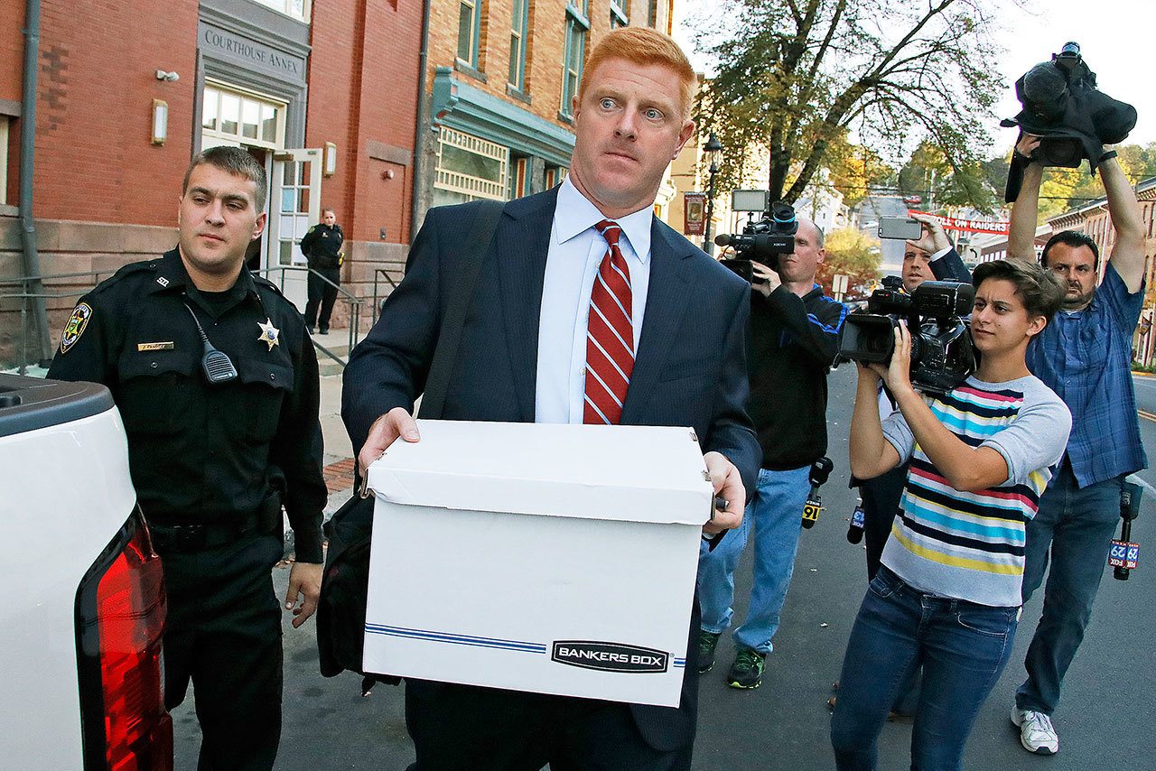 Former Penn State assistant football coach Mike McQueary (center) leaves the Centre County Courthouse Annex in Bellefonte, Pa. on Monday, Oct. 17, 2016, after the first day of his defamation and whistleblower lawsuit. (AP Photo/Gene J. Puskar)