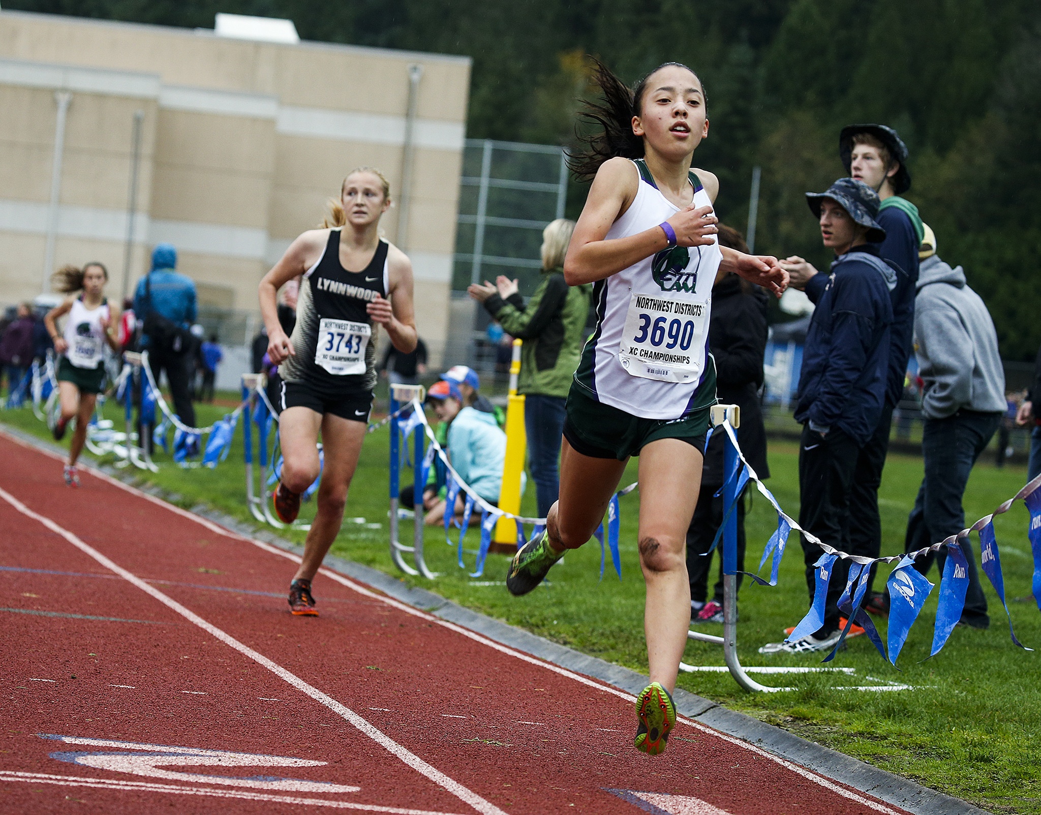 Edmonds-Woodway’s Yukino Parle (right) crosses the line to win the girls 3A District 1 cross country meet at South Whidbey High School on Saturday. Parle fell late in the race, but got up and still claimedvictory on the muddy and hilly course on Whidbey Island. (Ian Terry / The Herald)