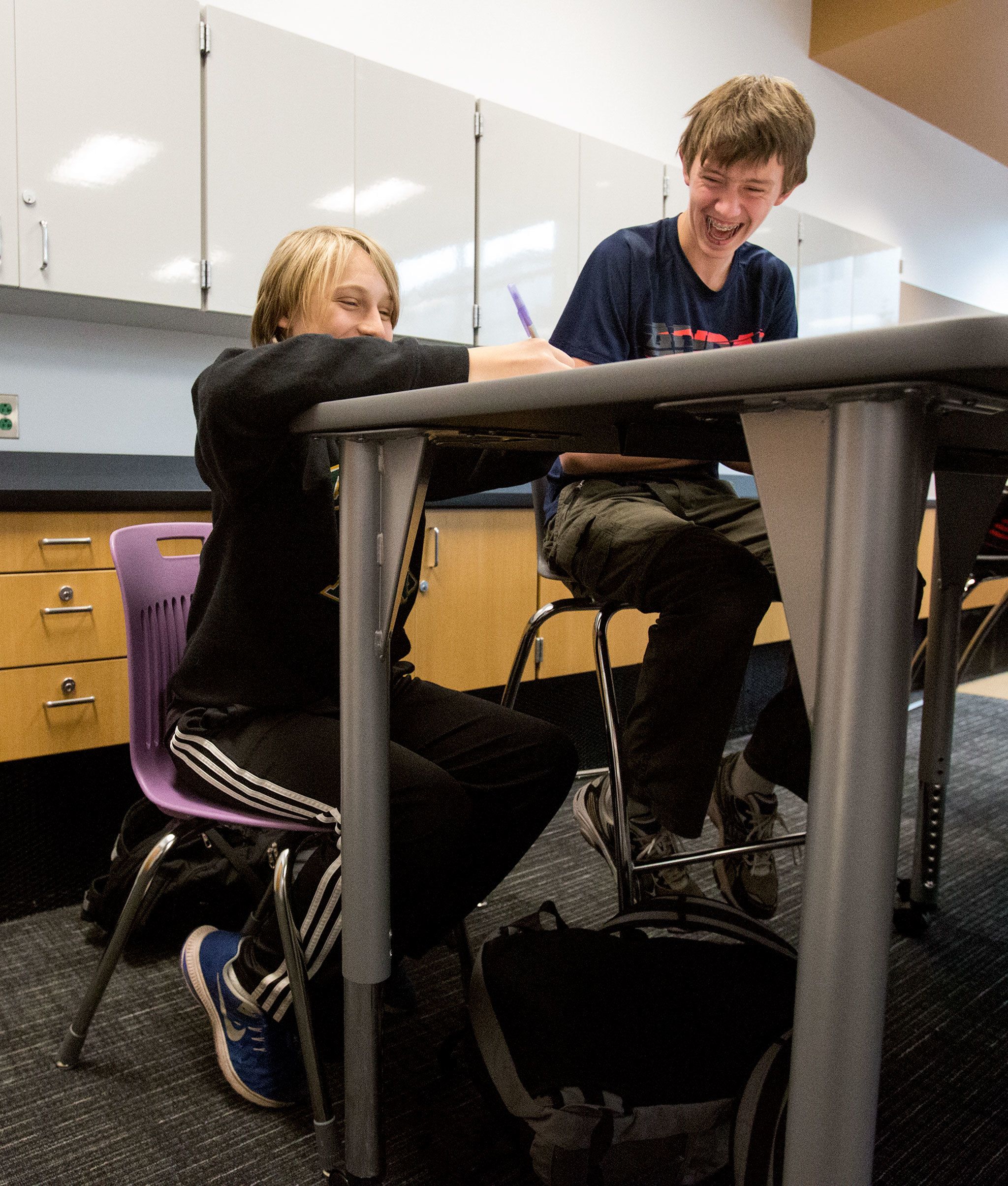 Leota Junior High eighth graders Elliott Tobin (left) and Jake Mullins laugh as they test out different chairs and desks at North Creek High School on Wednesday in Bothell. The students tested and graded three different sets of chairs and desks that the Northshore School District may purchase for the new high school. (Andy Bronson / The Herald)