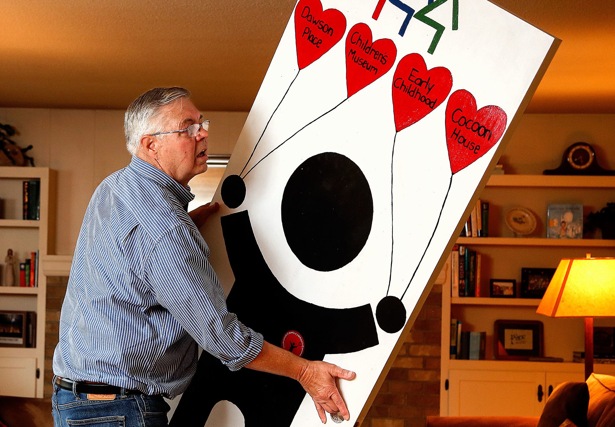 At his home in Everett Thursday, Chris Hoiby moves a door-full of reasons to celebrate the 30th anniversary of the Snohomish County Children’s Commission in preparation for next week’s event, which will honor past and present volunteers. (Dan Bates / The Herald)