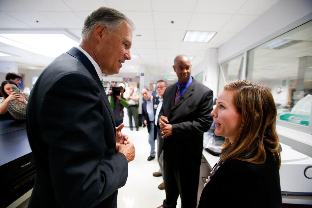 The Washington State Patrol forensic scientist Kristina Hoffman talks with Gov. Jay Inslee while giving a tour of the lab in Marysville on Oct. 6. (Dan Bates / The Herald)
