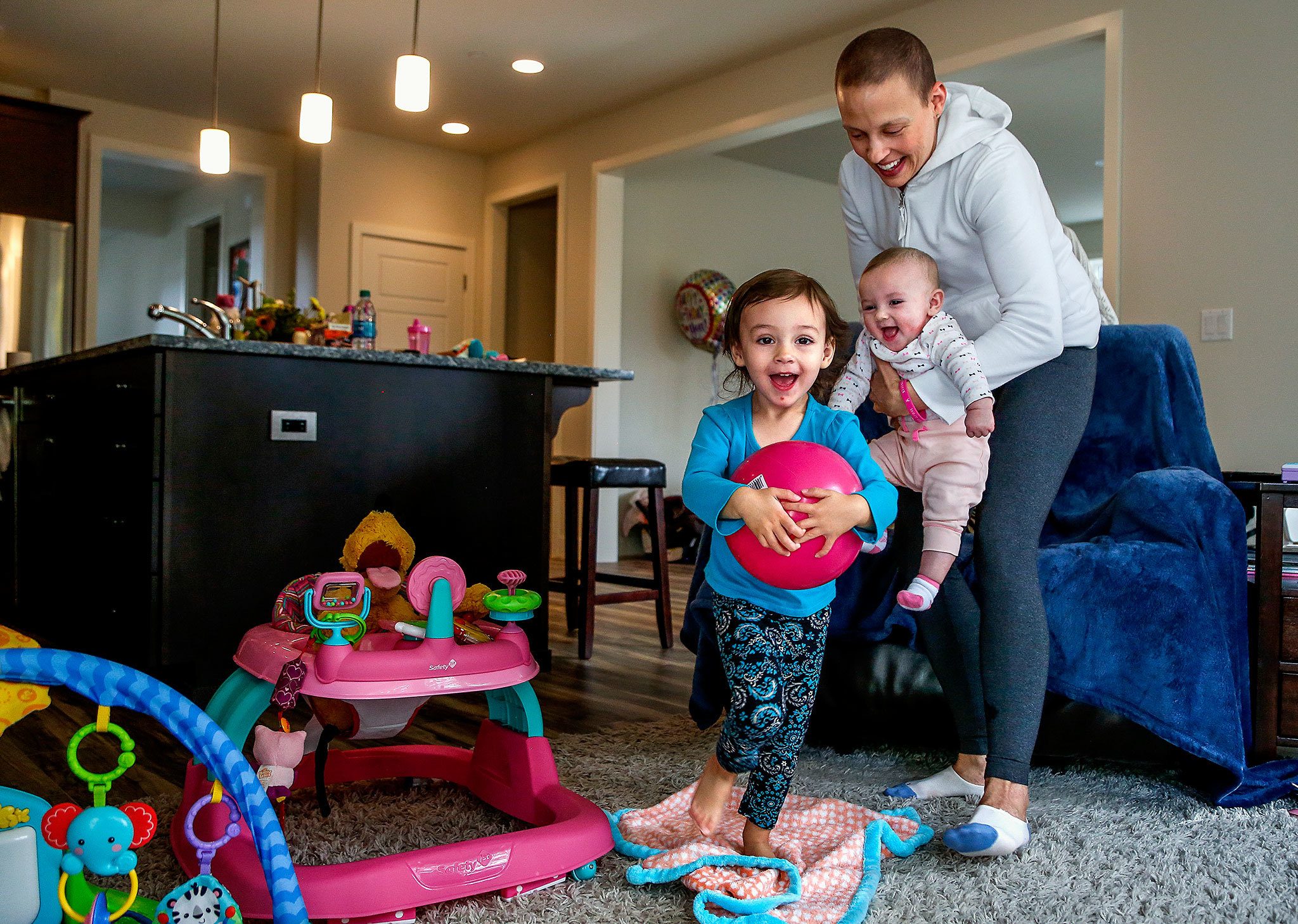 Carrying 4-month-old Haven, Apryl Roberts chases 2-year old Charlee around the house Wednesday, to the delight of all three. (Dan Bates / The Herald)