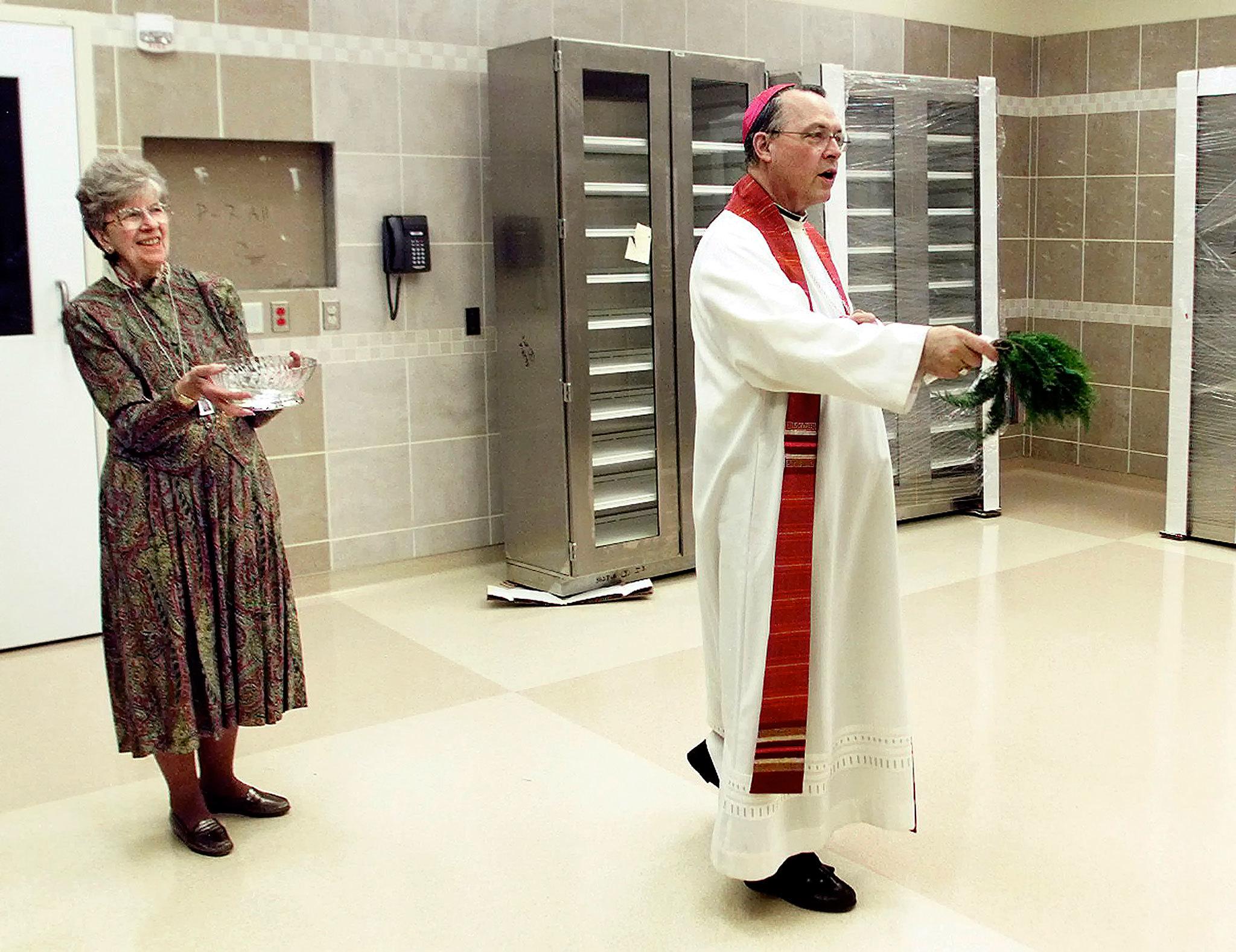 Sister Dorothy Klingele assists then-Seattle Archbishop Alexander Brunett with holy water during a 2002 blessing of an operating room in the Family Maternity Center at Providence Regional Medical Center Everett’s Pavilion for Women and Children. Klingele, who served in health care with the Sisters of Providence for decades, died Oct. 15 at age 90. (Stephanie S. Cordle / Herald File)
