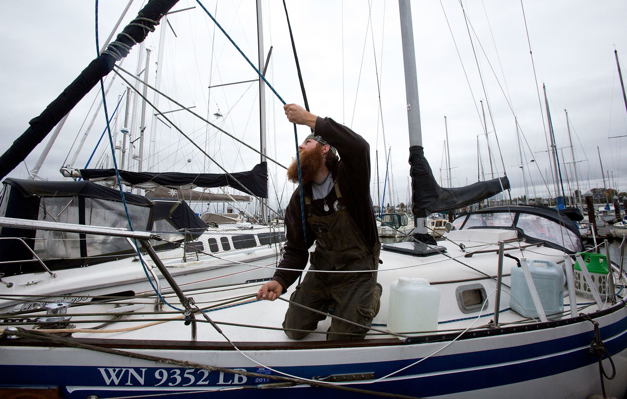 Boat owner Nicholas Bell tightens a sail as he prepares for expected high winds later in the Everett Marina on Thursday. Bell, who lives aboard his 32-foot cutter, said he saw 10 sails flapping on other boats during the last big storm. “That’s a lot of damage,” he said. (Andy Bronson / The Herald)