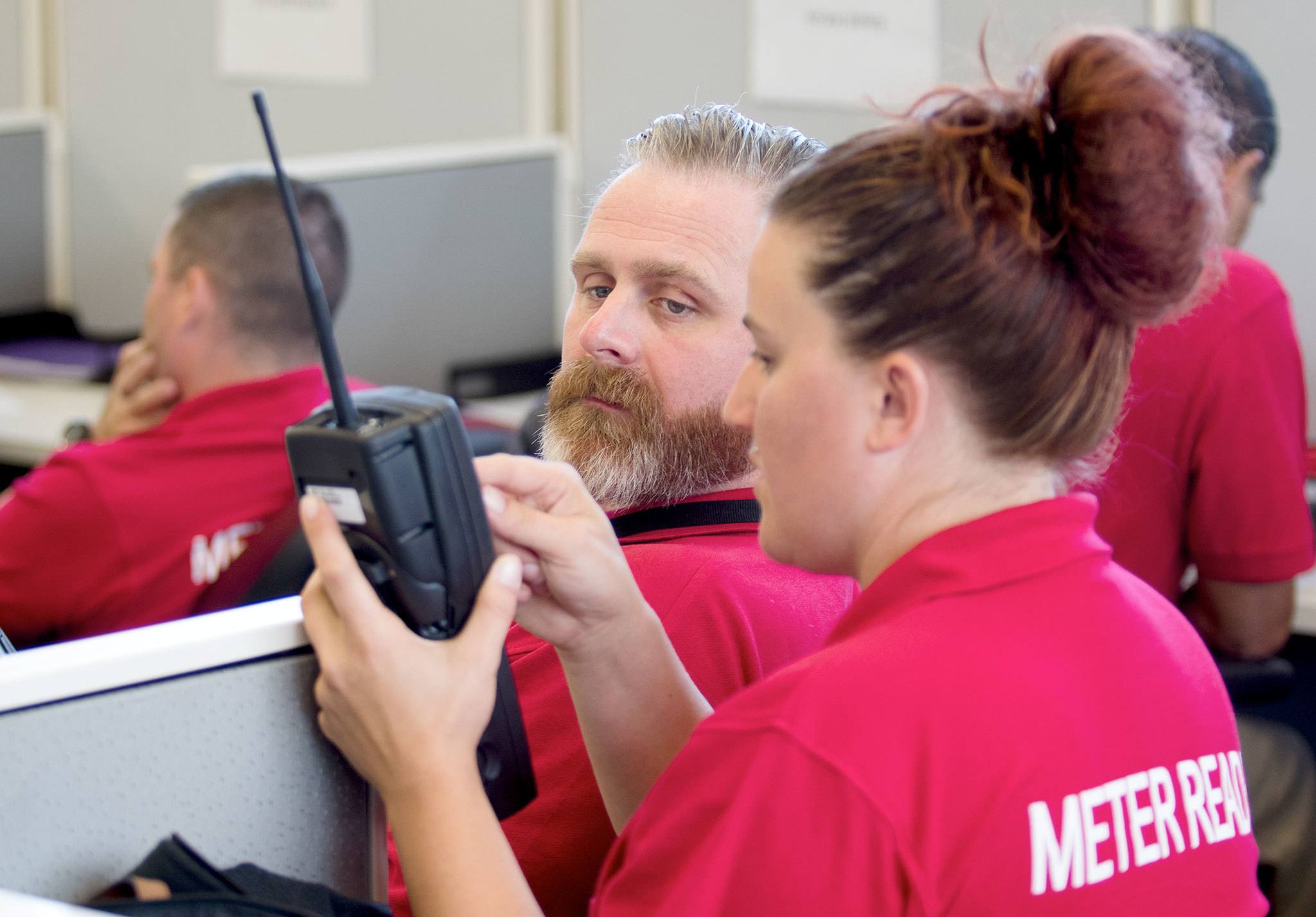 TruCheck meter reader Jessica Knypstra shows a program to Matthew Mathias as they learn to use new readers in Mountlake Terrace on Wednesday. TruCheck, a Kentucky-based contractor, was hired Snohomish County PUD to provide extra meter readers.(Andy Bronson / The Herald)