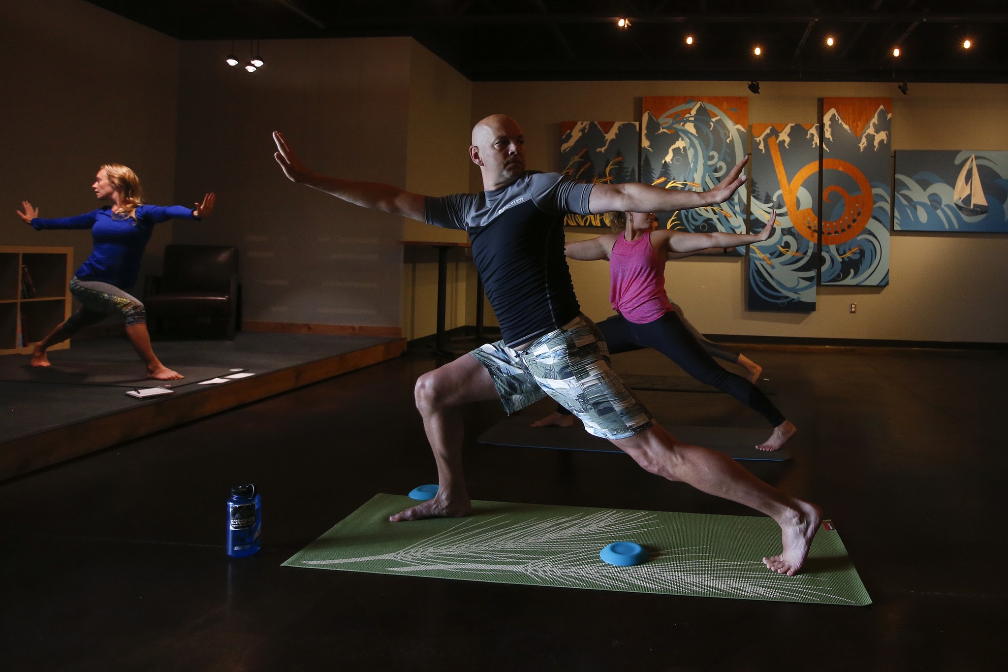 Bluewater Organic Distilling owner John Lundin (center) balances during a YogaMosa session on Saturday, Aug. 6. (Ian Terry / The Herald)