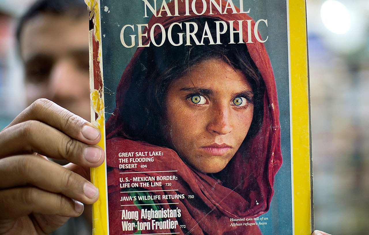 Pakistan’s Inam Khan, owner of a book shop, shows a copy of a magazine with the photograph of Afghan refugee woman Sharbat Gulla, from his rare collection in Islamabad, Pakistan, on Wednesday, Oct. 26. A Pakistani investigator says the police have arrested National Geographic’s famed green-eyed ‘Afghan Girl’ for having a fake Pakistani identity card. (AP Photo/B.K. Bangash)