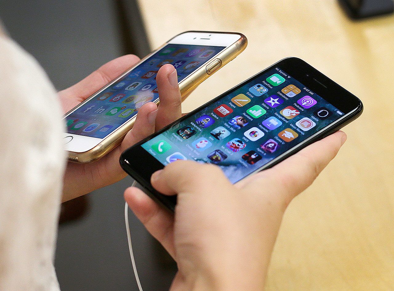 In this Sept. 16 photo, Lisa Gao, from Chicago, compares a new jet black iPhone 7, right, with her iPhone 6 at an Apple Store in Chicago. (AP Photo/Kiichiro Sato, File)