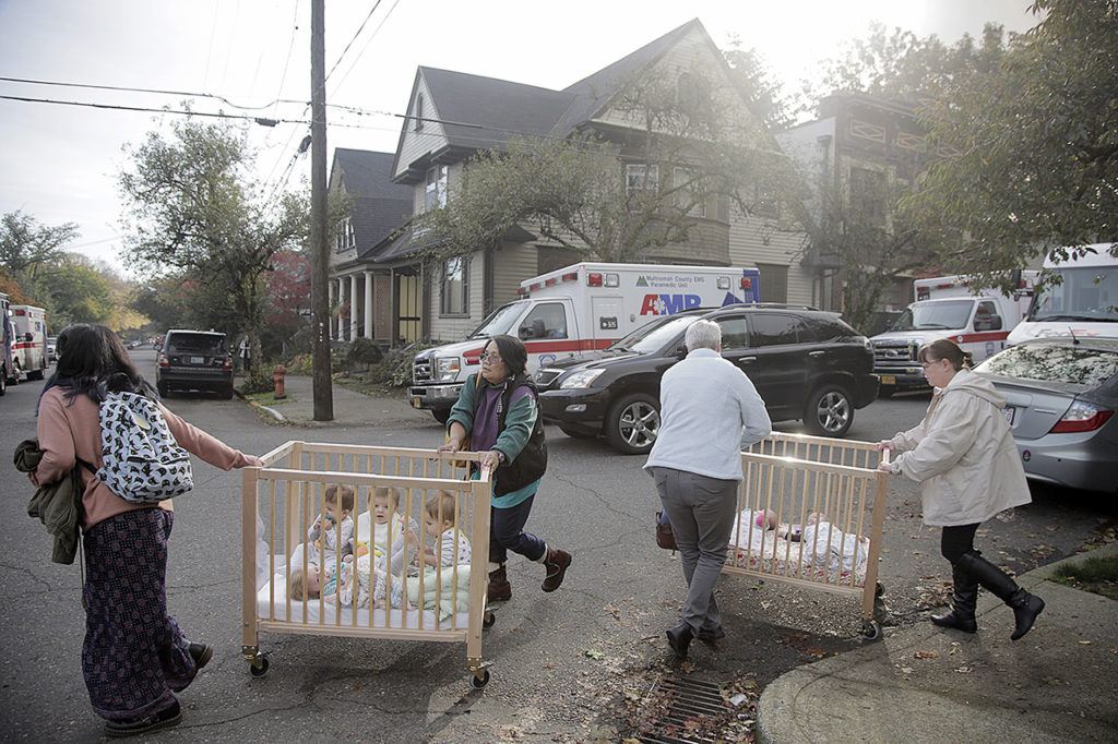 People evacuate children in the area of Northwest 23rd Avenue and Glisan Street after a gas explosion Wednesday, Oct. 19, in Portland, Oregon. (Stephanie Yao Long/The Oregonian via AP)
