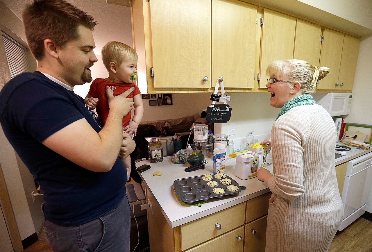 In this Thursday, Oct. 13, 2016, photo, Shavonne Henry, right, greets her 7-month-old son, Jordan, as her husband, Michael Henry, brings him into the kitchen after a nap at their apartment in Vancouver, Wash. Nearly half of all Americans aged 18 to 30 have nothing in retirement savings and no access to a traditional pension, according to a survey. “I feel pretty good about our future,” says Shavonne Henry. “The reason we got to saving at all was I took a finance class in college, and part of the course was: If you want to have the kind of retirement you want to have, you should start saving at 20,” she says. “I don’t think that’s talked about enough.” (AP Photo/Don Ryan)