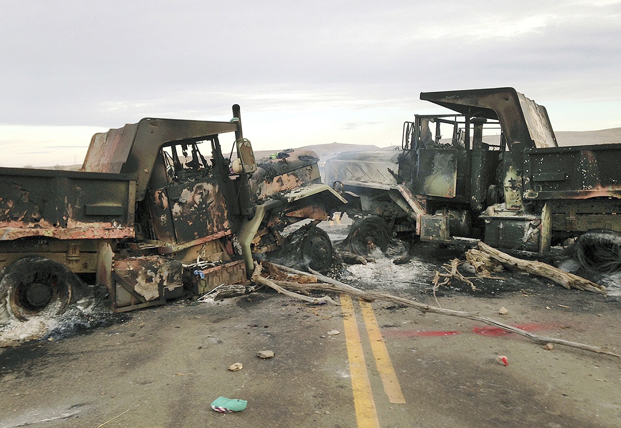 The burned hulks of heavy trucks sit on Highway 1806 near Cannon Ball, North Dakota, on Friday, Oct. 28, near the spot where protesters of the Dakota Access pipeline were evicted from private property a day earlier. Authorities say protesters burned several pieces of construction equipment Thursday during a chaotic confrontation with law enforcement. (AP Photo/James MacPherson)