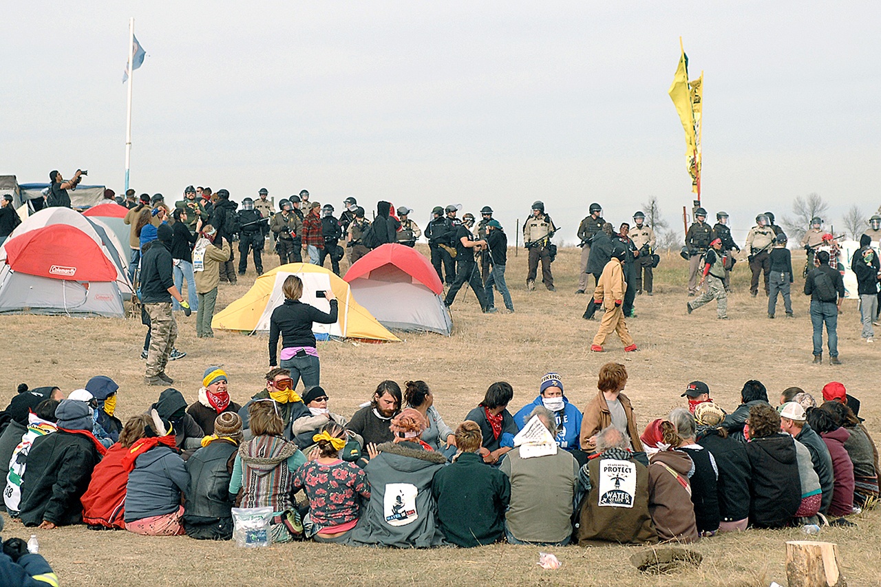 Dakota Access Pipeline protesters sit in a prayer circle at the Front Line Camp as a line of law enforcement officers make their way across the camp to remove the protesters and relocate to the overflow camp a few miles to the south on Highway 1806 in Morton County, North Dakota, on Thursday. (Mike McCleary/The Bismarck Tribune)