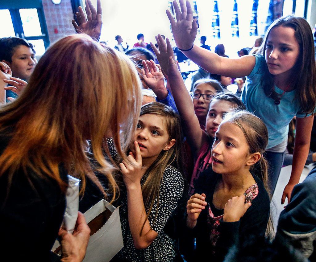 Faces of young Evergreen Middle School students reveal a sense of anticipation as well as concentration on an answer to the question: name one thing you can do at a library besides check out books? The anticipation may have more to do with ice cream bars that assistant principal Carmen Boggs is holding. (Dan Bates / The Herald)
