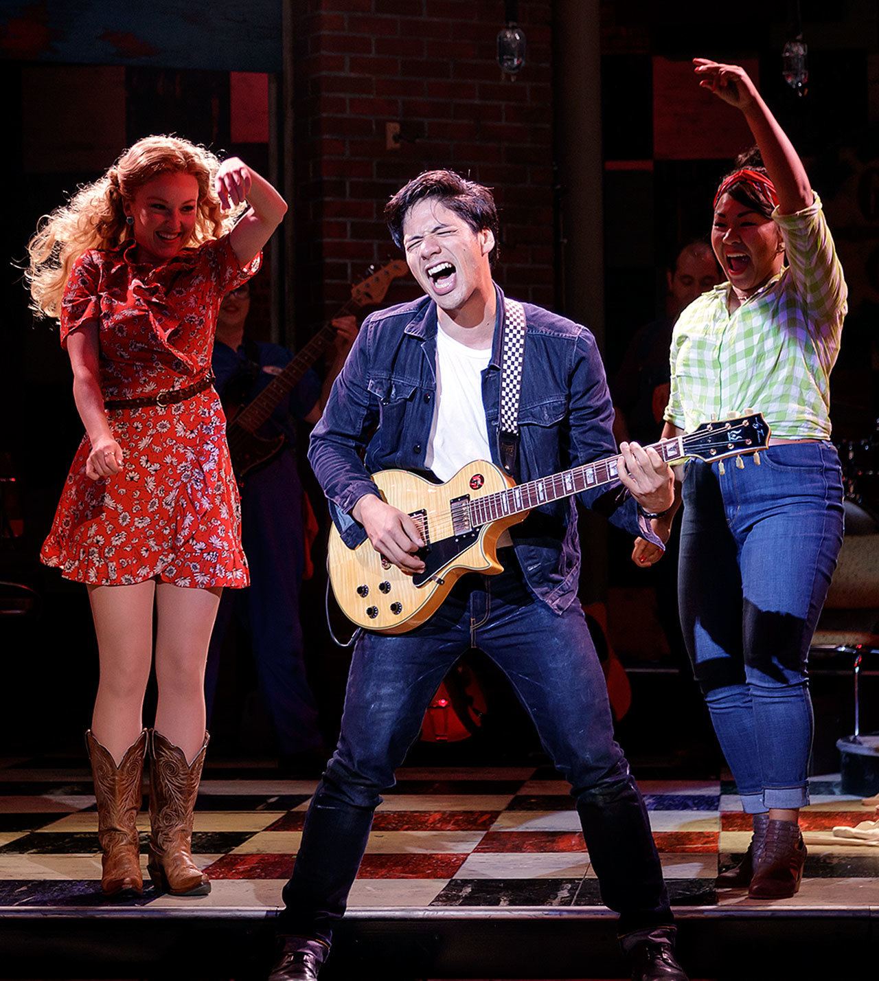 The character Jackson makes his guitar sing while the Cupp sisters dance in the Village Theatre show at Everett Performing Arts Center. (Village Theatre photo)