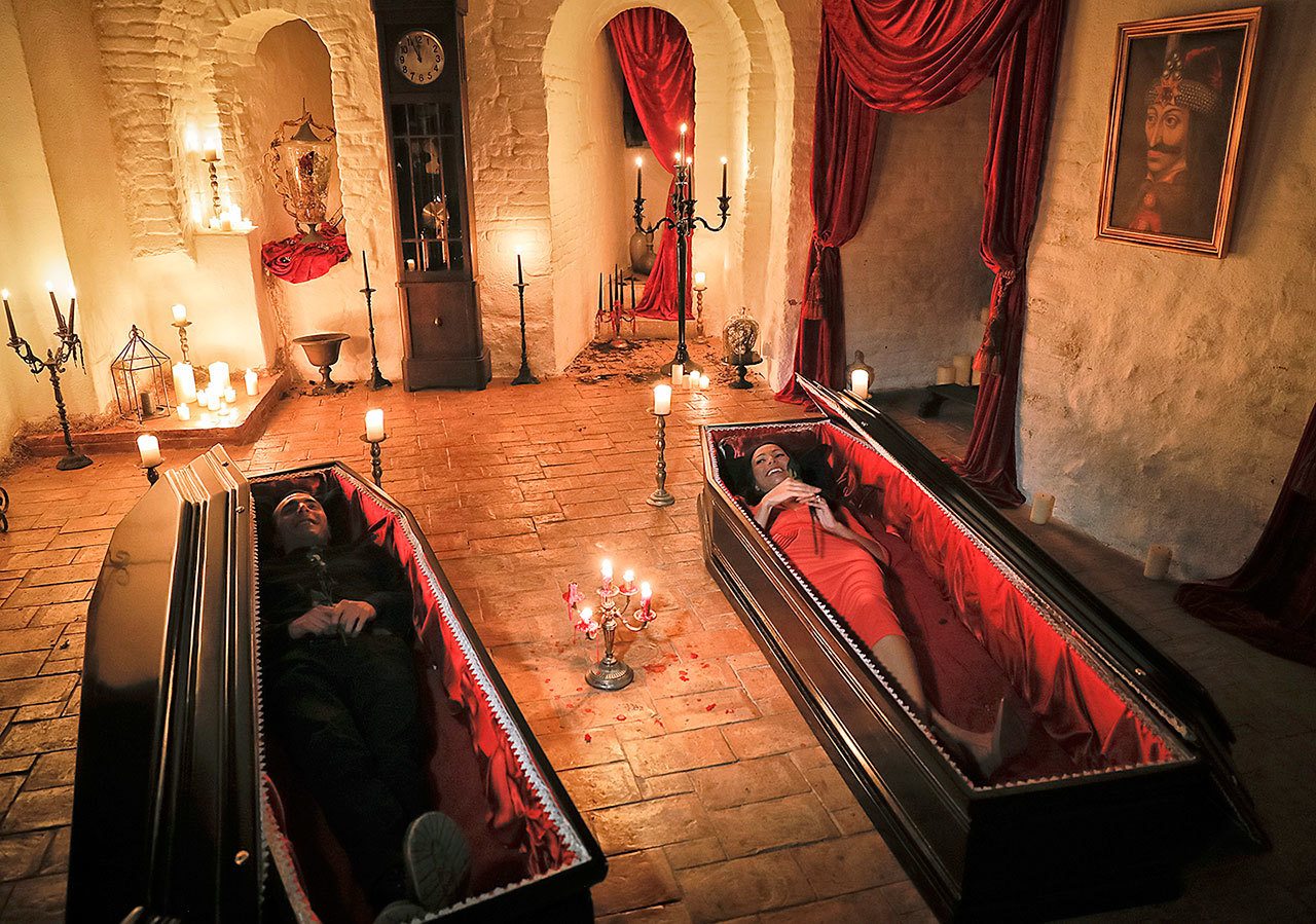 Tami Varma, right, and her brother Robin, the grandchildren of Devendra Varma, a scholar of English gothic tales and an expert in vampire lore, pose in coffins, at the Bran Castle, in Bran, Romania, on Monday, Oct. 31. The Canadian brother and sister are passing Halloween night curled up in red velvet coffins in the Transylvanian castle that inspired the Dracula legend, the first time in 70 years anyone has spent the night in the gothic fortress, after they bested 88,000 people who entered a competition hosted by Airbnb to get the chance to dine and sleep at the castle in Romania. A portrait of medieval prince Vlad the Impaler is placed on the wall. (AP Photo/Vadim Ghirda)
