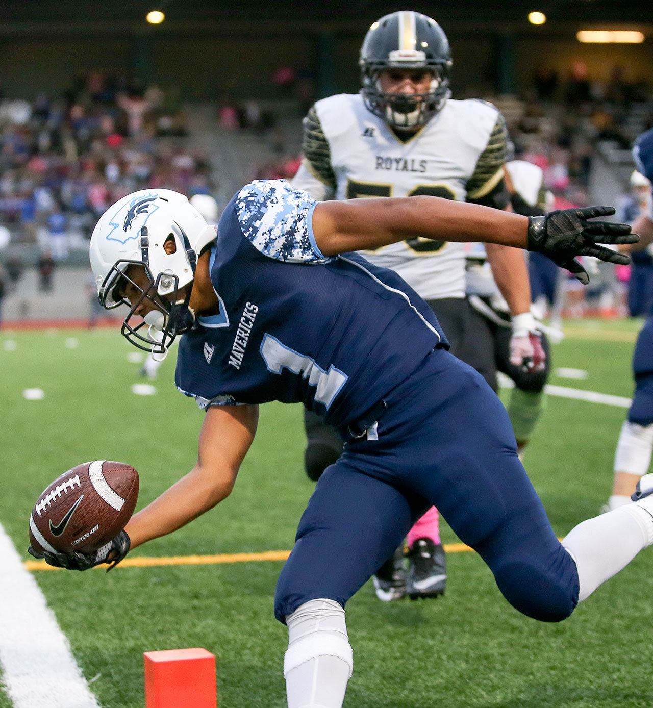 Meadowdale’s Jashon Butler reaches across the goal line for a touchdown on a 24-yard interception return in the second quarter with Lynnwood’s Harris Cutuk closing in during a game Friday night at Edmonds Stadium. The Mavericks beat the Royals 55-28 for their fifth consecutive win. (Kevin Clark / The Herald)