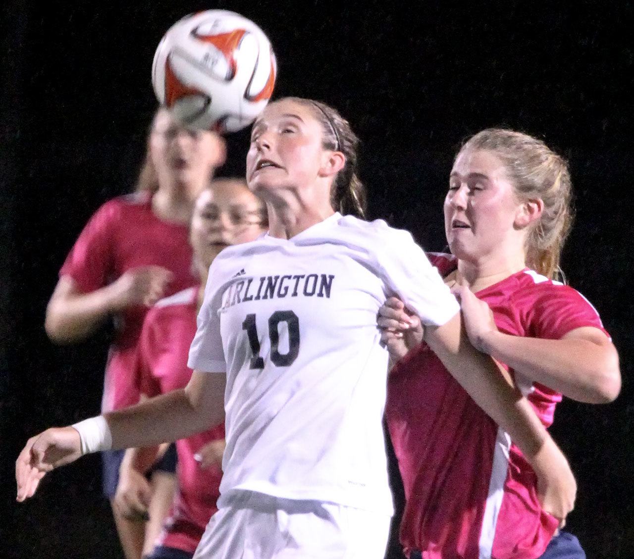 Arlington’s Courtney Arnold heads the ball with Meadowdale’s Sarah Elder defending in the first half of play Thursday night at John Larson Stadium in Artlington on October 6, 2016. (Kevin Clark / The Herald)