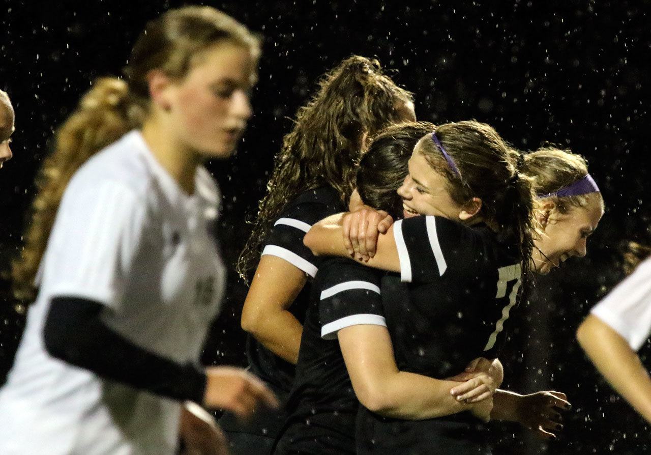 Kamiak’s Sarah Nehring, right, hugs teammate Jenny Wrobel after Wrobel’s goal in the closing minutes of the match with Lake Stevens’ Peyton Moenoa, left, makes her way back to the line Thursday night at Lake Stevens High School on October 13, 2016.(Kevin Clark / The Herald)