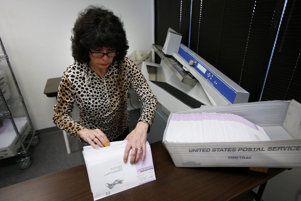 Janice Denk organizes envelopes before they are placed in a machine designed to open them in batches while working at the Snohomish County ballot return center in Mukilteo on Thursday. (Ian Terry / The Herald)
