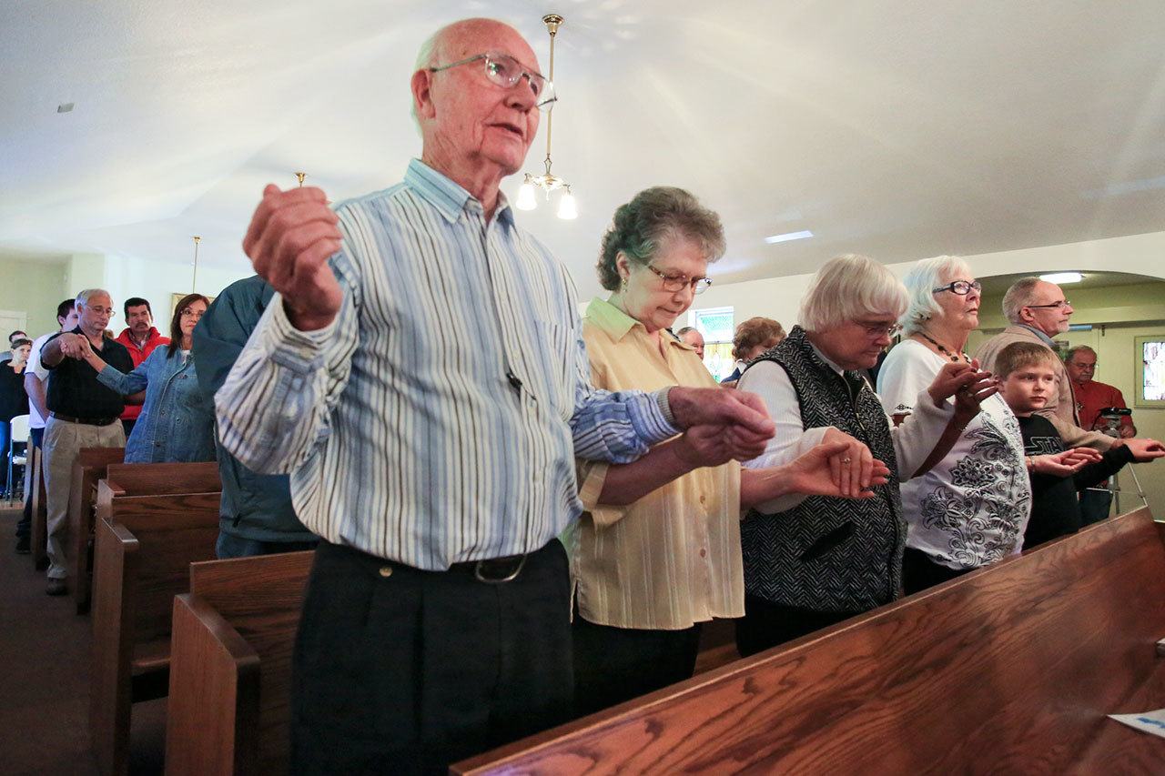 Hal Ring(from left), Joan Ring and Mary Sequa pray during the 100 year celebration Mass at St. John Vianney Catholic Church in Darrington in September. (Kevin Clark / The Herald)