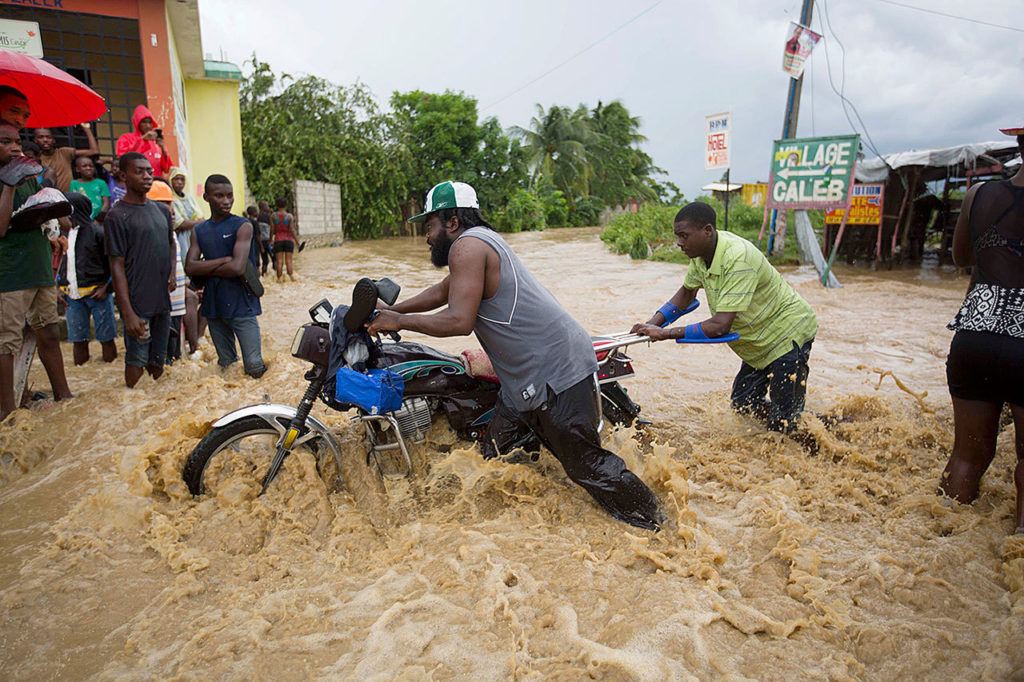 Men push a motorbike through a street flooded by a river that overflowed from heavy rains caused by Hurricane Matthew in Leogane, Haiti, on Wednesday. Rescue workers in Haiti struggled to reach cutoff towns and learn the full extent of the death and destruction caused by Hurricane Matthew as the storm began battering the Bahamas on Wednesday and triggered large-scale evacuations along the U.S. East Coast. (AP Photo/Dieu Nalio Chery)
