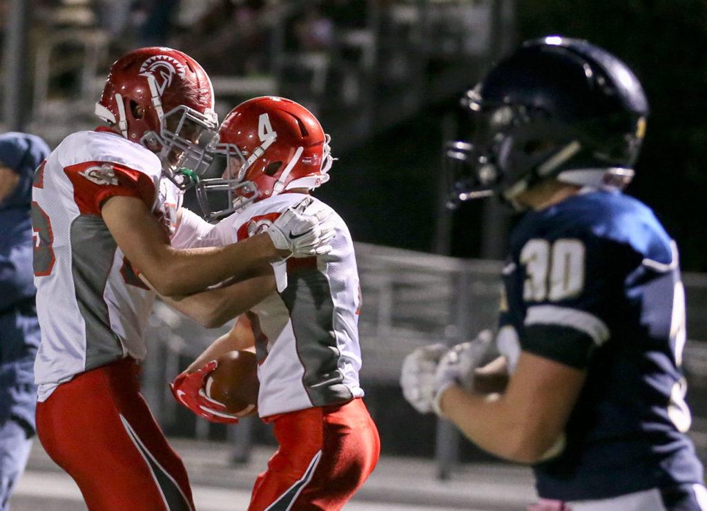 Stanwood’s Gavin Schwietzer congratulates teammate Trygve DeBoer on his touchdown reception with Arlington’s Devon Nutter (far right) walking away during the annual Stilly Cup football game Friday night in Arlington. (Kevin Clark / The Herald)
