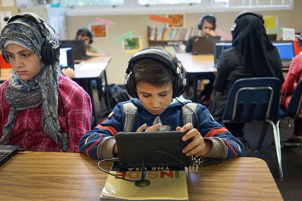 In this Oct. 4 photo, students Samah Hussein, 13, and Abdulraheem Qadour, 11, study on their laptops in a class filled with refugee children at Cajon Valley Middle School in El Cajon, California. (AP Photo/Christine Armario)

