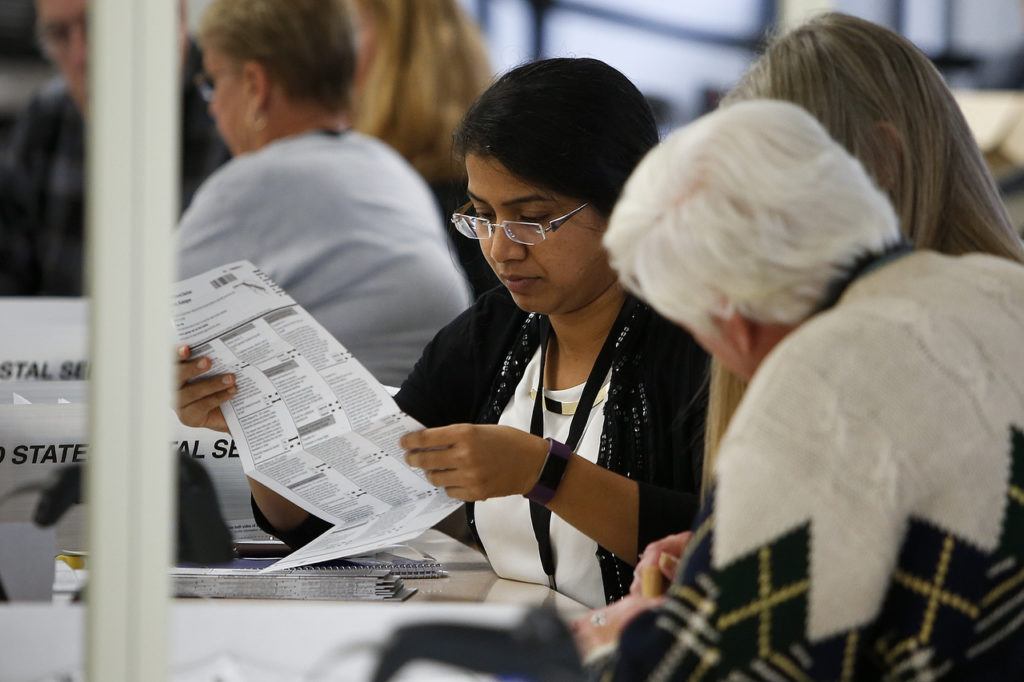 Workers examine ballots at the Snohomish County ballot return center in Mukilteo on Thursday. (Ian Terry / The Herald)
