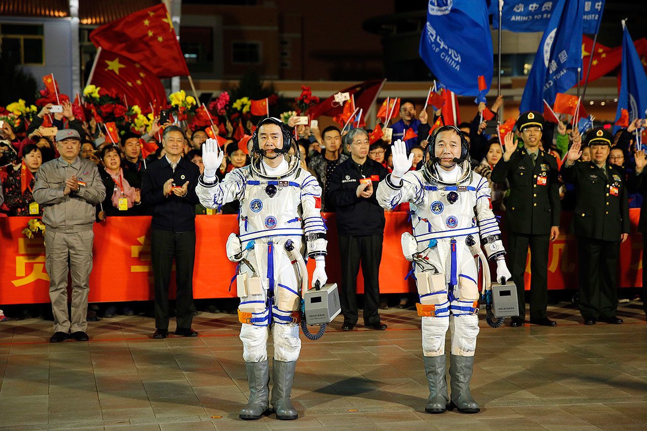 Chinese astronauts Chen Dong (left) and Jing Haipeng wave farewell to the crowd before getting on Shenzhou 11 spacecraft at the Jiuquan Satellite Launch Center in northwest China on Monday. (Chinatopix via AP)