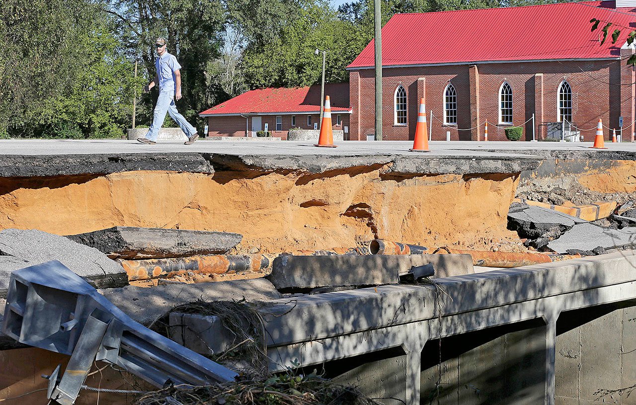 A man walks across a road damaged by floodwaters caused by rain from Hurricane Matthew in Fayetteville, North Carolina, on Sunday. Hurricane Matthew’s torrential rains triggered severe flooding in North Carolina on Sunday as the deteriorating storm made its exit to the sea, and thousands of people had to be rescued from their homes and cars. (Chuck Burton / Associated Press)