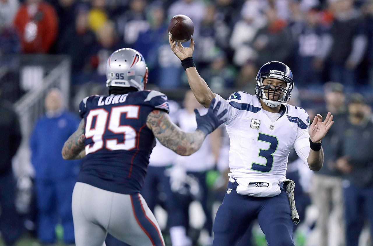 Seattle Seahawks quarterback Russell Wilson throws as New England Patriots defensive end Chris Long applies pressure during Sunday’s game. (AP Photo/Charles Krupa)