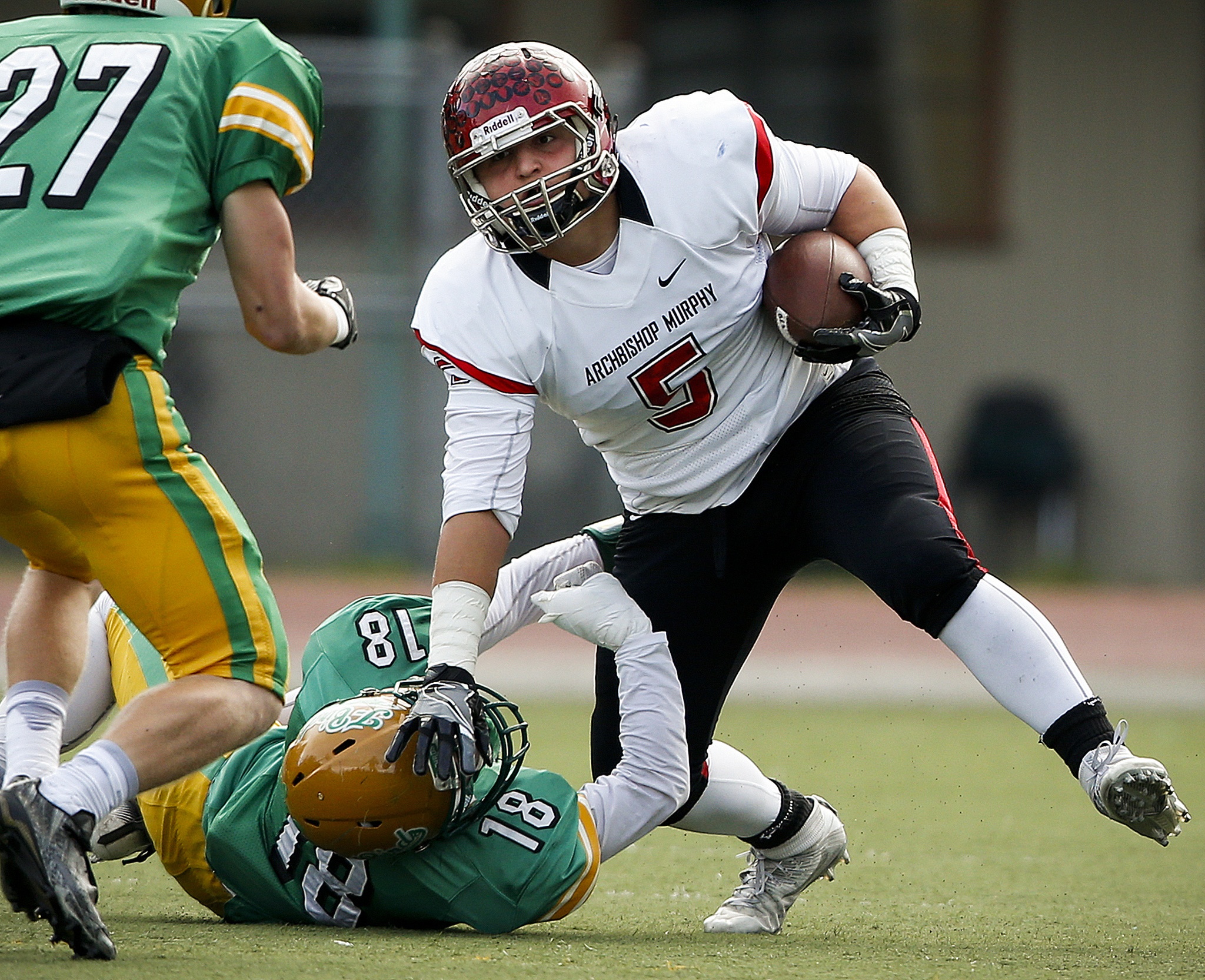 Archbishop Murphy’s Ben Hines (right) stiff-arms Tumwater’s Andrew May to the ground during a 2A state playoff game at Tumwater High School on Saturday. (Ian Terry / The Herald)