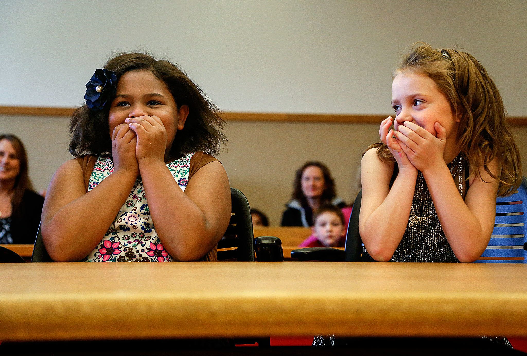 Kortnei, 9 (left) and Miah Schramm, 8, can hardly conceal their delight as they sit down at a big table facing Judge David A. Kurtz on Friday in Snohomish County Superior Court. The two young girls not only scored a mom and a dad on National Adoption Day, but also landed each other. Sisters! (Dan Bates / The Herald)