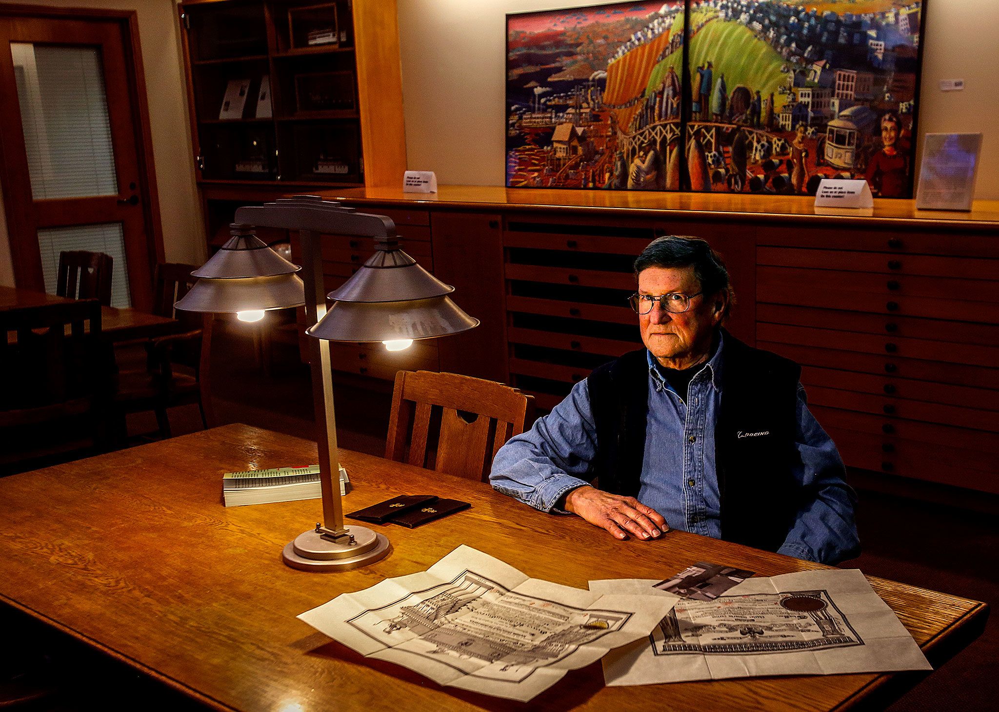 Frank Melder Jr, 77, shares what he knows about his grandfather Charles Curtiss, the National Guard lieutenant killed in the Everett Massacre, and what became of his grandmother after the Nov. 5, 1916, shootings. In the background is Camano Island artist Jack Gunter’s painting, “The Everett Massacre,” now on loan to the Everett Public Library. (Dan Bates / The Herald)