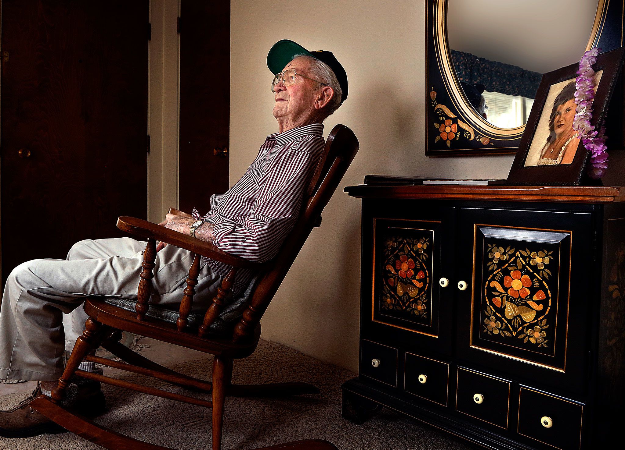 Raymond Lund, 95, a World War II veteran who served in Europe, including landing on the beach at Normandy on D-Day, sits in a rocker at his home in Stanwood. A framed photograph of his wife, Aileen sits on a cabinet behind him with a lei hanging over it. Aileen, who died last year, and Ray were married for 65 years. (Dan Bates / The Herald)