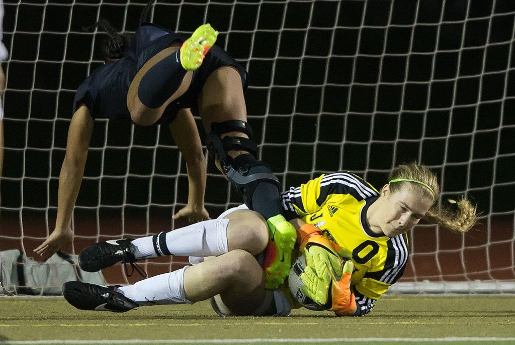 Jackson goalkeeper Kayleigh Sedlacek makes a save as Union’s MaKayla Woods goes flying over her in Jackson’s 2-1 win in a first-round state playoff game Tuesday at Everett Memorial Stadium. (Andy Bronson / The Herald)
