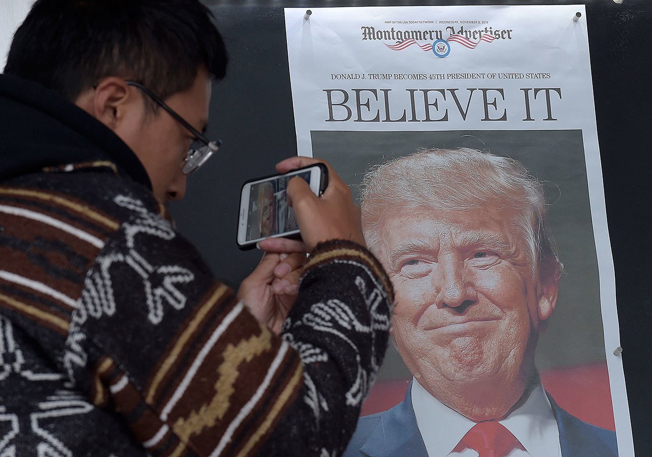 Zheng Gao of Shanghi, China, photographs the front pages of newspapers on display outside the Newseum in Washington the day after Donald Trump won the presidency on Nov. 9. (AP Photo/Susan Walsh)